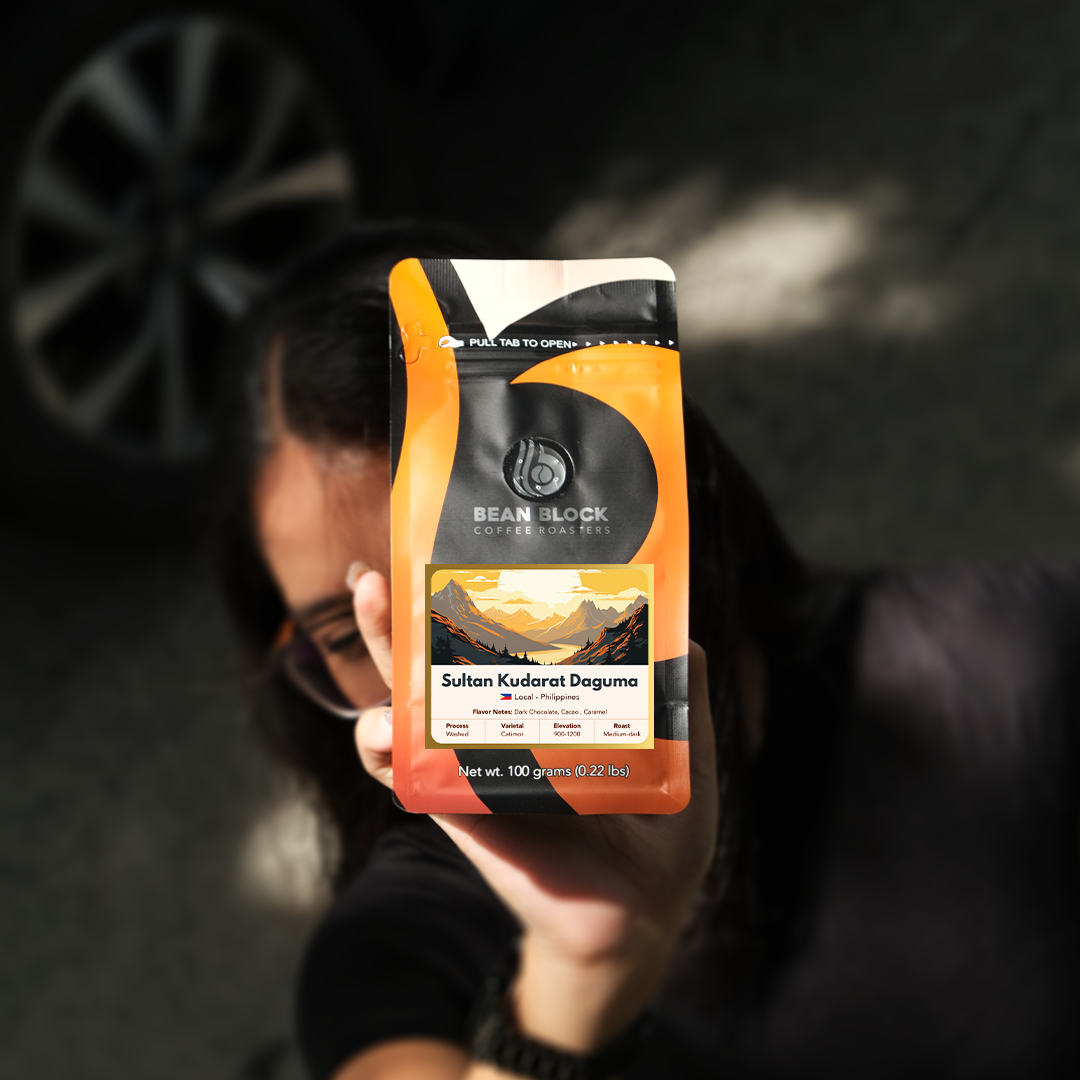 Person holding a Bean Block Coffee Roasters Sultan Kudarat 100g coffee package with a blurred background