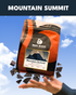 Bean Block Coffee Roasters Mountain Summit 250g coffee package with a hand holding it against a blue sky background.