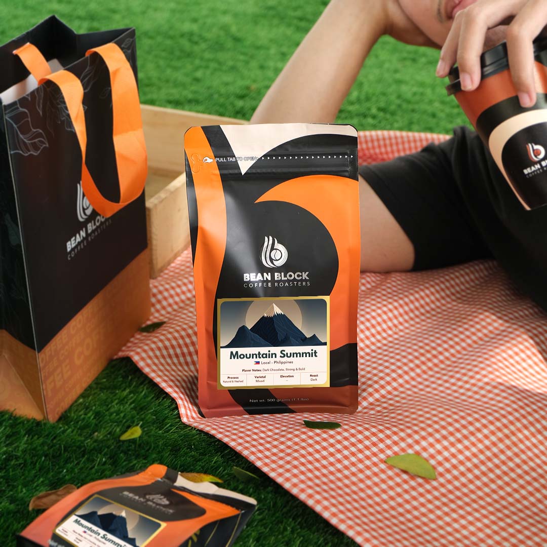 Bean Block Mountain Summit 500g coffee packaging on a picnic blanket with a person holding a coffee cup.