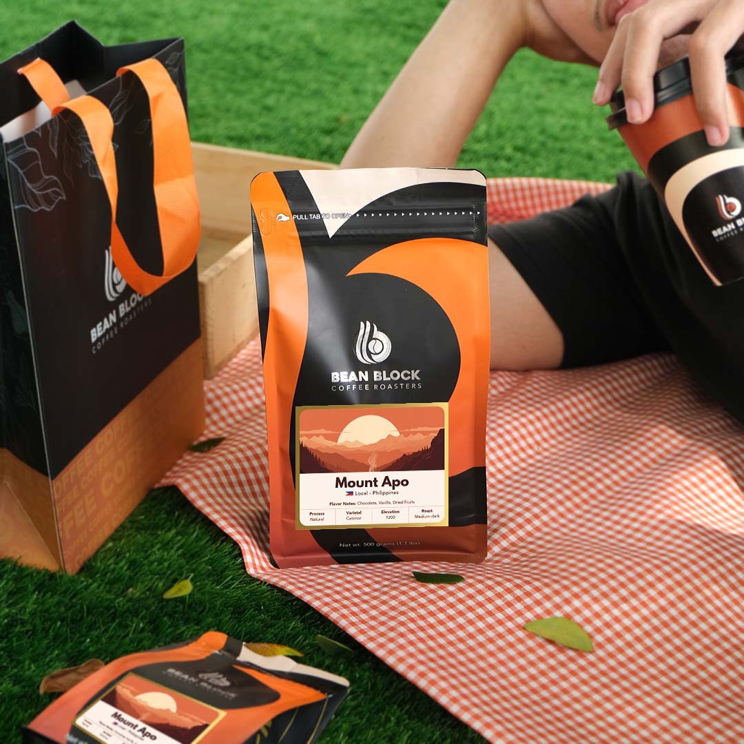 Bean Block coffee package on a picnic blanket with a person holding a coffee cup. 500g bean block coffee roasters coffee bean pouch of Mount Apo